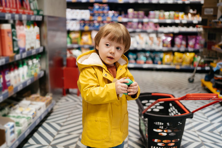 Child in the market with a grocery cart buys a ball