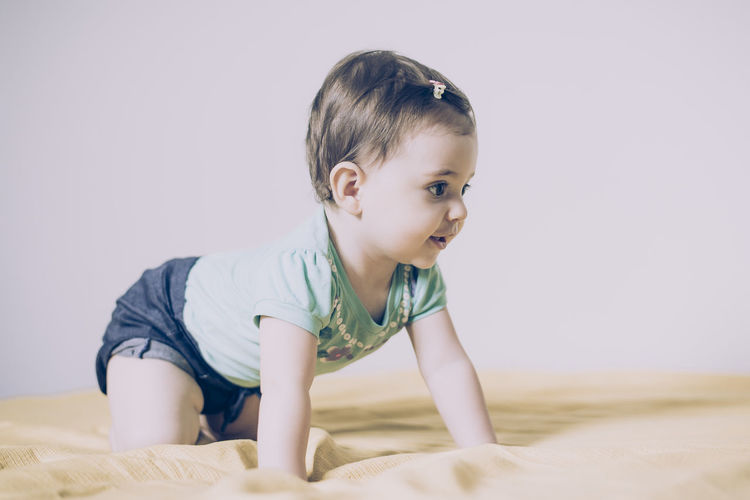 Cute baby girl crawling on bed girl at home