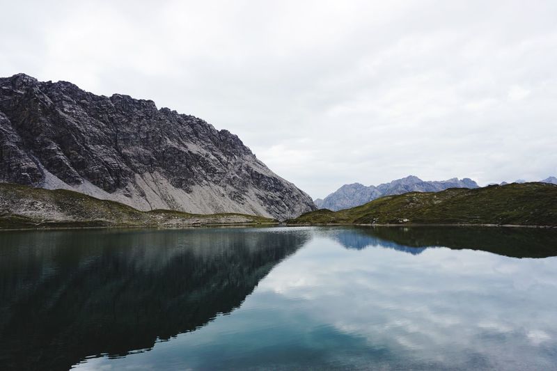 Scenic view of lake by mountains against sky