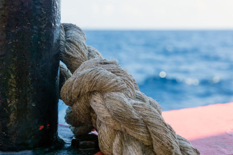 Close-up of rope tied on wooden post in sea