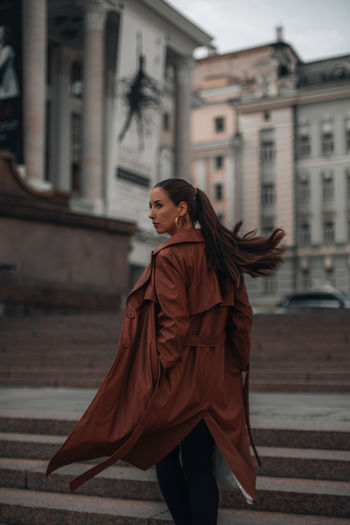 Outdoor autumn portrait of young elegant fashionable woman wearing trendy brown leather coat
