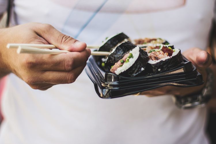 Midsection of man with sushi holding in container