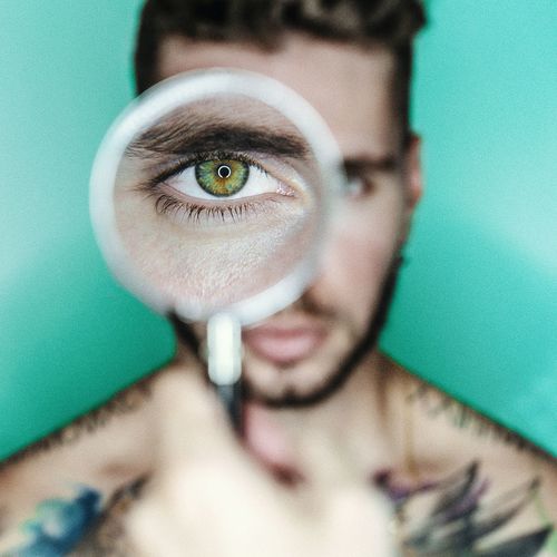 Portrait of young man holding magnifying glass