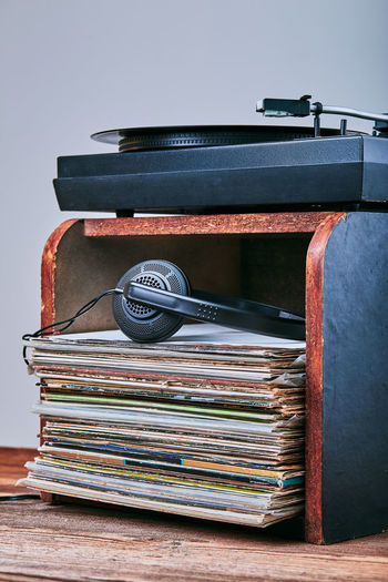 Close-up of records and headphones in box with turntable against gray background