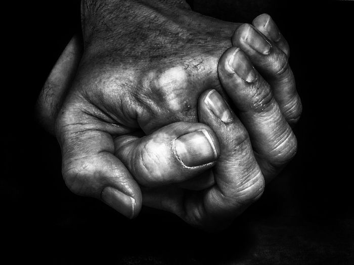 Close-up of man holding hands over black background
