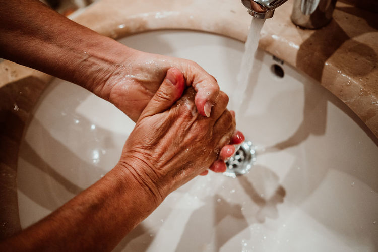 Cropped image of person washing hands in sink