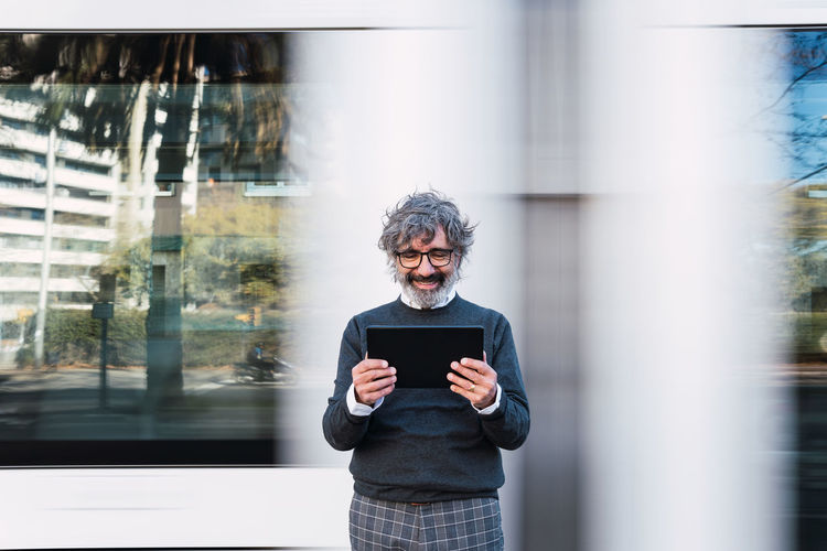 Mature man using digital tablet while waiting for train. businessman waiting for train