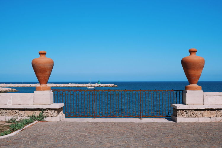 Vase against sea against clear blue sky