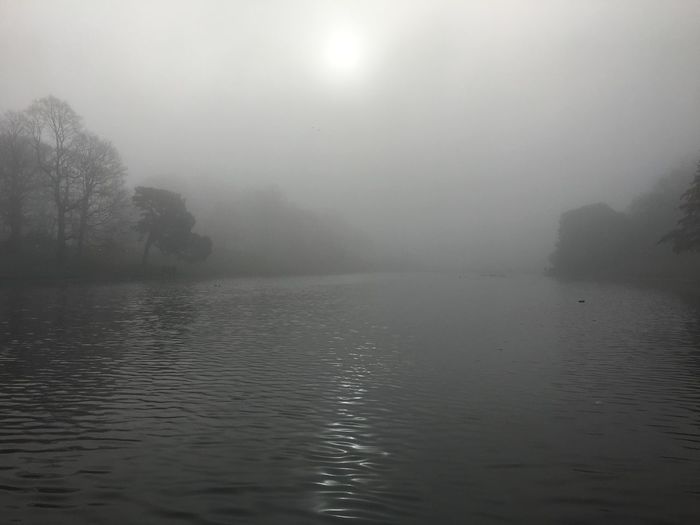 Scenic view of lake against sky at foggy weather