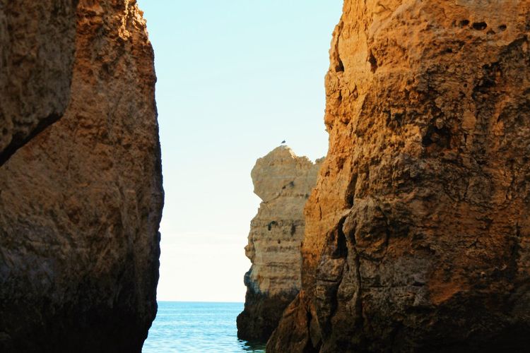 Rock formations by sea against clear sky
