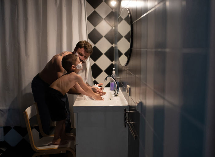 Father and son washing hands while shaving faces
