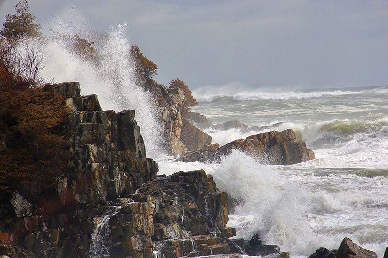Waves splashing on rocks against sky