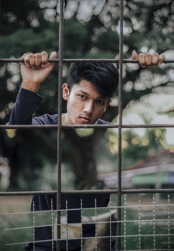 Portrait of young man behind fence