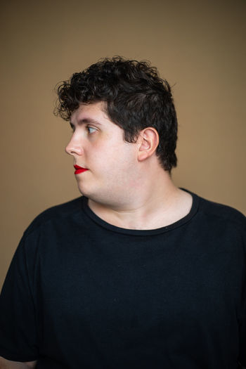 PORTRAIT OF YOUNG MAN LOOKING AWAY AGAINST WALL