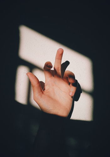 Close-up of woman showing middle finger against wall