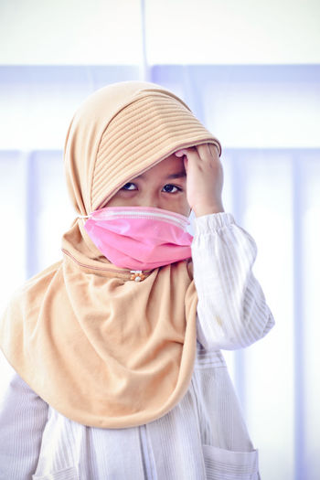 Portrait of cute girl wearing mask standing at home