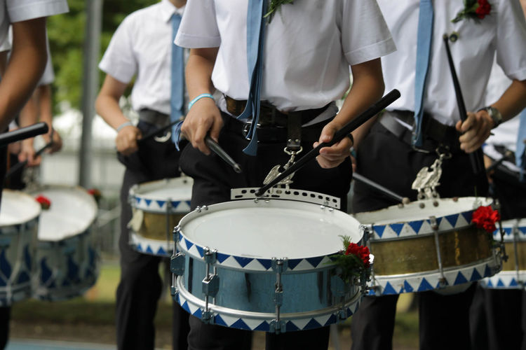 Midsection of men playing drums