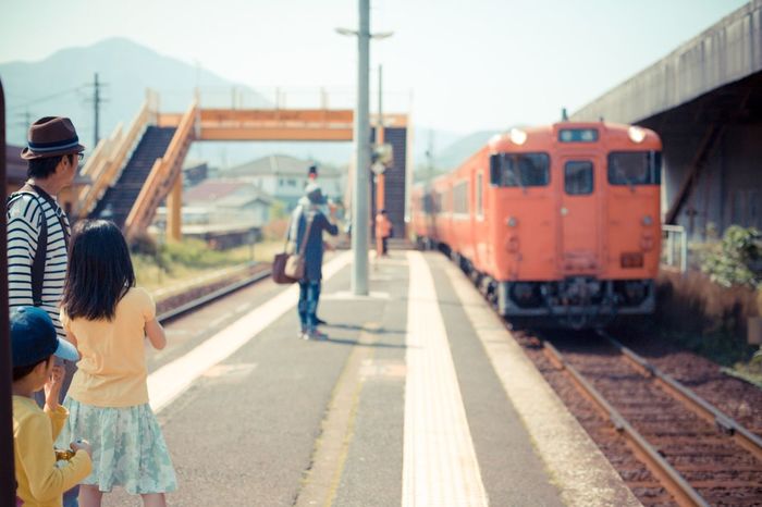 Father with children looking at train arriving at railroad platform