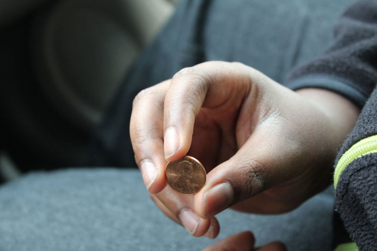 Midsection of person holding coin while sitting indoors