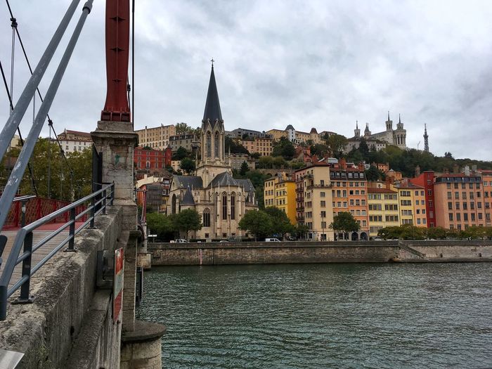 View of buildings by river against sky in city