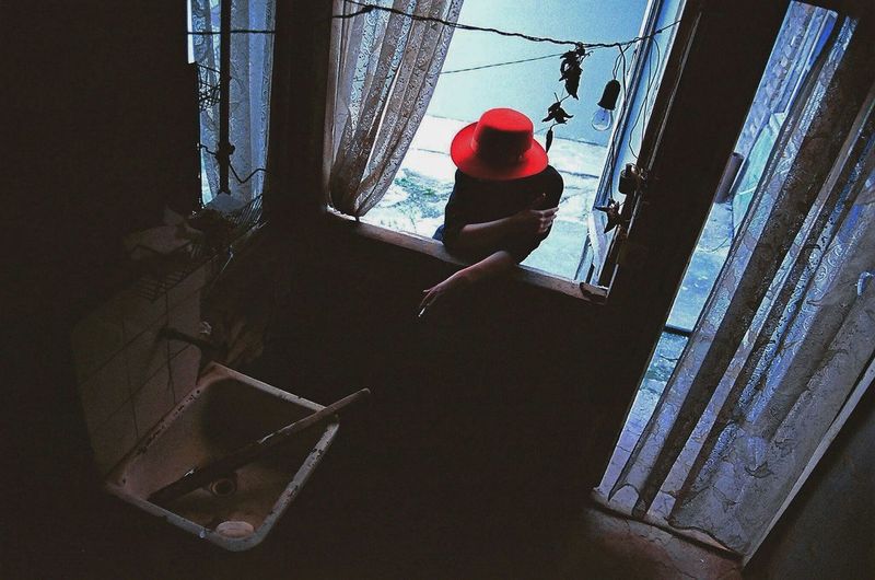 High angle view of woman smoking while standing by window outside house