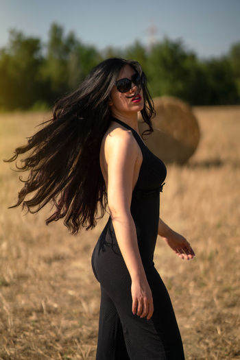 Young woman wearing sunglasses standing on field