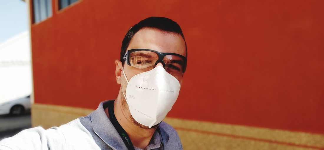 Portrait of man wearing eyewear and mask against wall