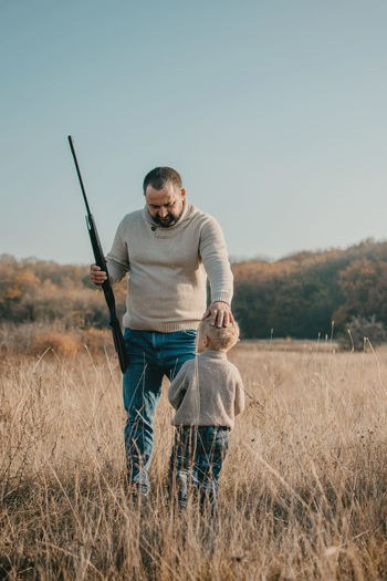 Father's day. father with gun showing something to son while hunting on a nature. happy family