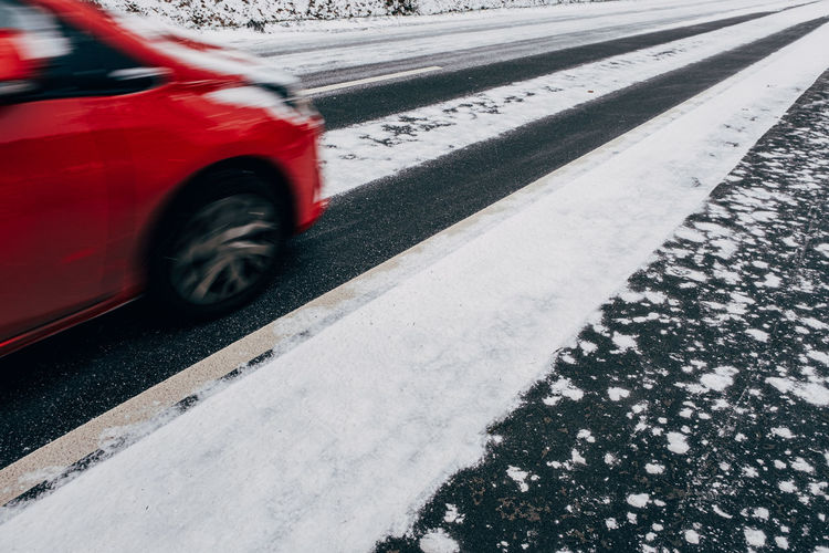 Side view of blurred fast red car on snowy road