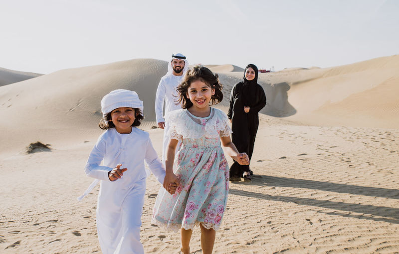 Portrait of happy family walking on sand dune