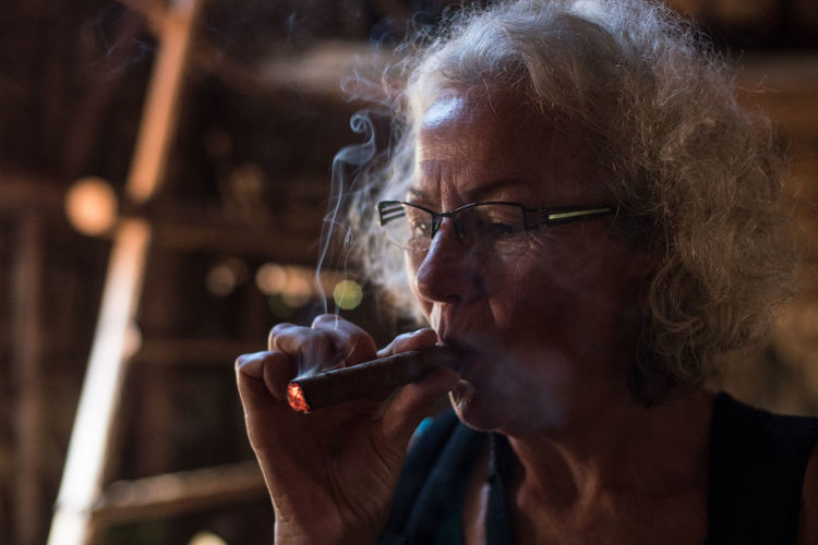 Close-up portrait of a old woman smoking cigar