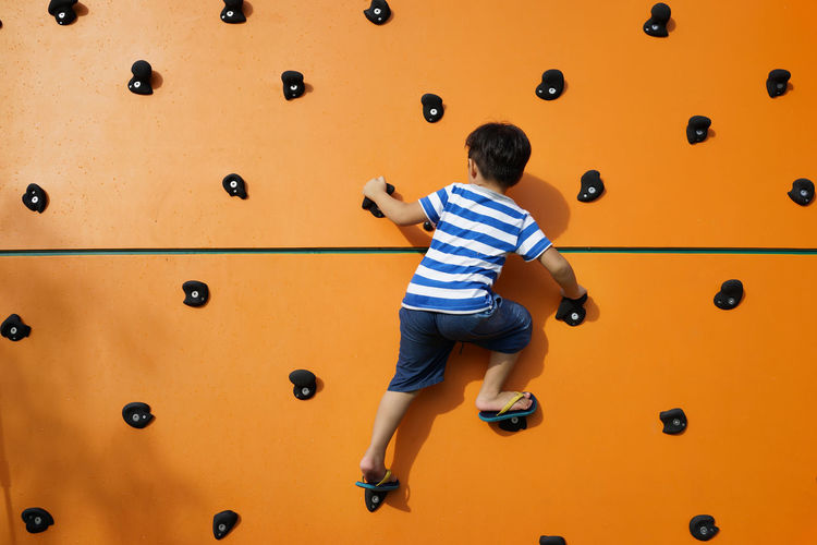 Rear view of boy climbing wall