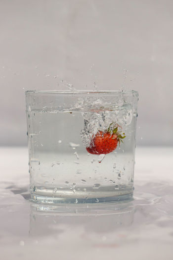 Close-up of strawberry over glass against water