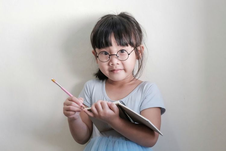 Portrait of cute girl holding eyeglasses