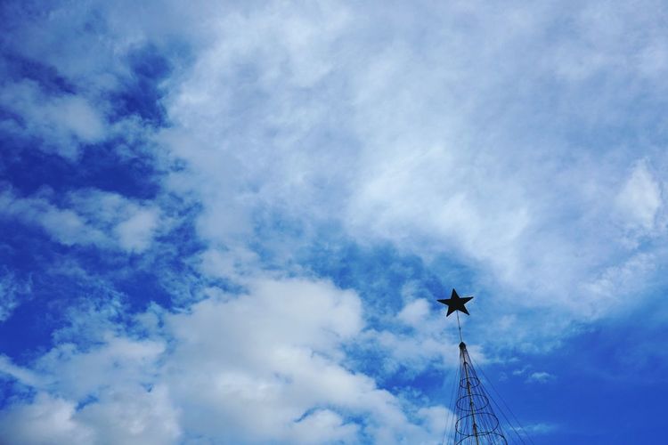Low angle view of weather vane against blue sky
