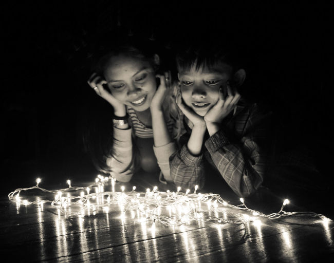 Brother and sister looking at illuminated string lights