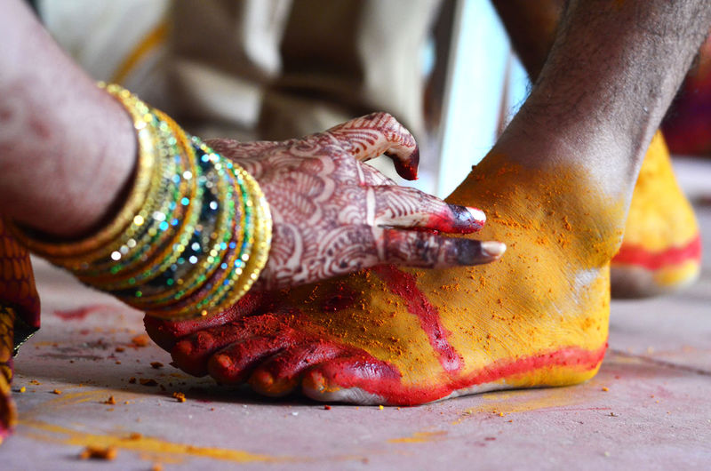 Close-up of female hand applying turmeric powder on male feet