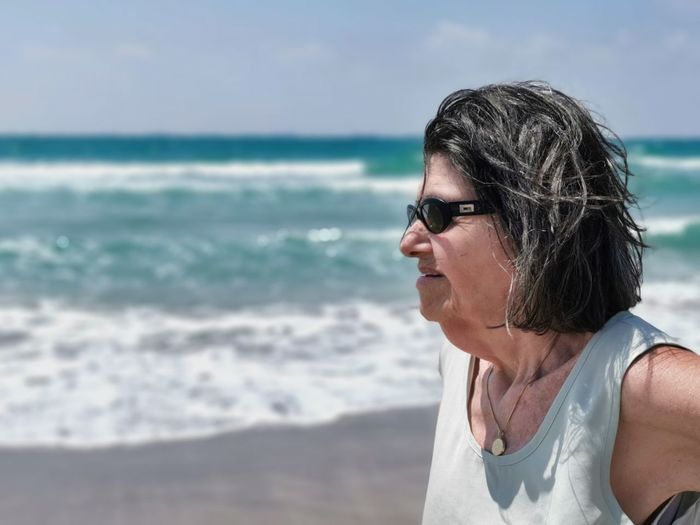 Woman wearing sunglasses at beach against sky