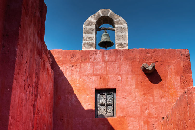 Low angle view of a rooftop bell in the santa catalina monastery, arequipa, peru against blue sky 