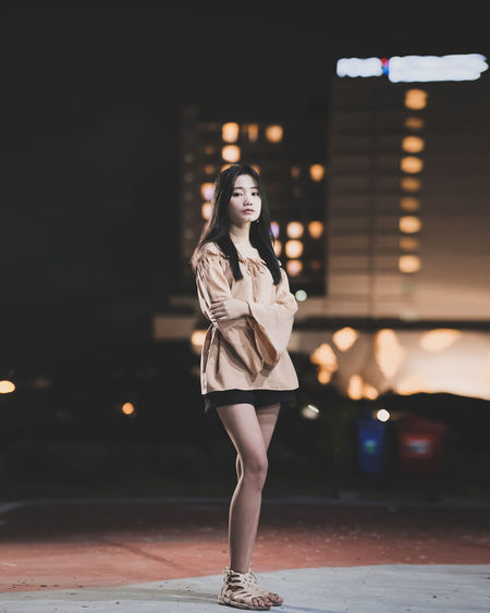 Portrait of young woman standing outdoors at night