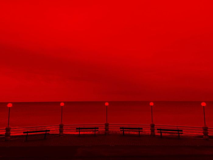By the sea, evening light, red vision, horizon over the sea and street lamps 