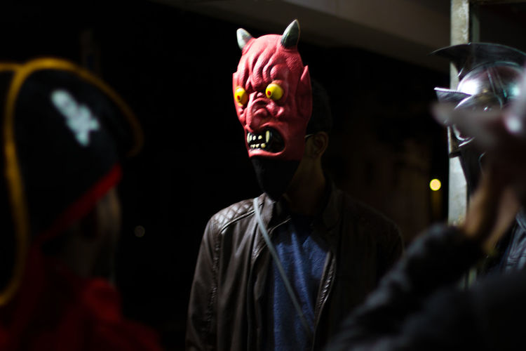 Close-up of man wearing mask of a demon or a devil at night in a street in the city. 