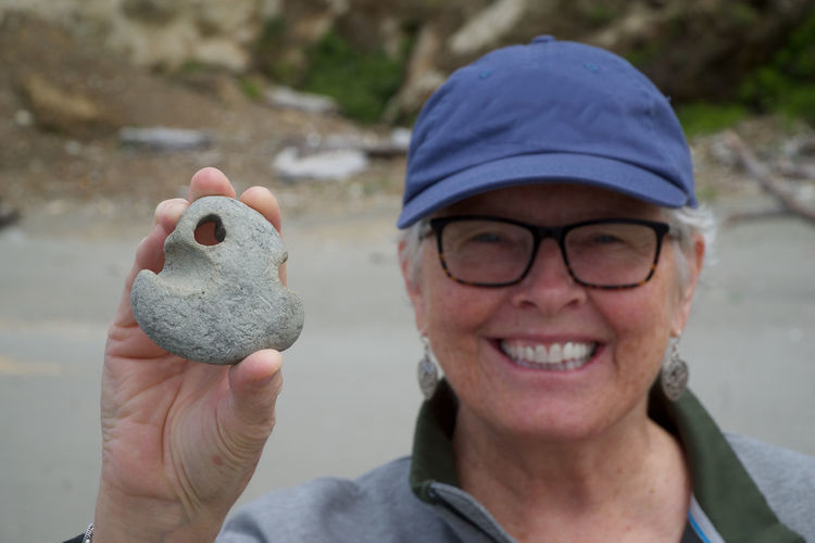 Portrait of smiling woman wearing eyeglasses while holding stone