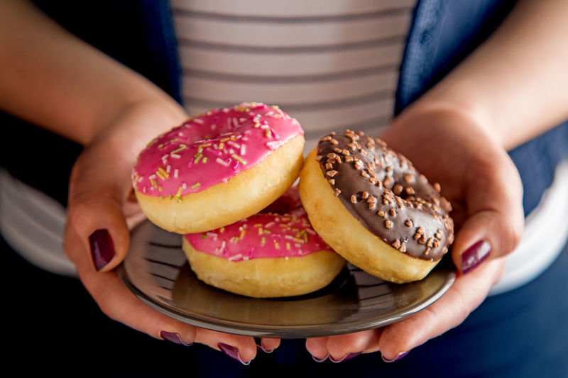 Midsection of woman holding donuts in plate
