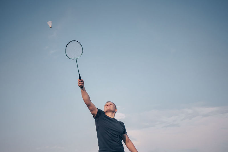 Low angle view of person playing badminton against sky