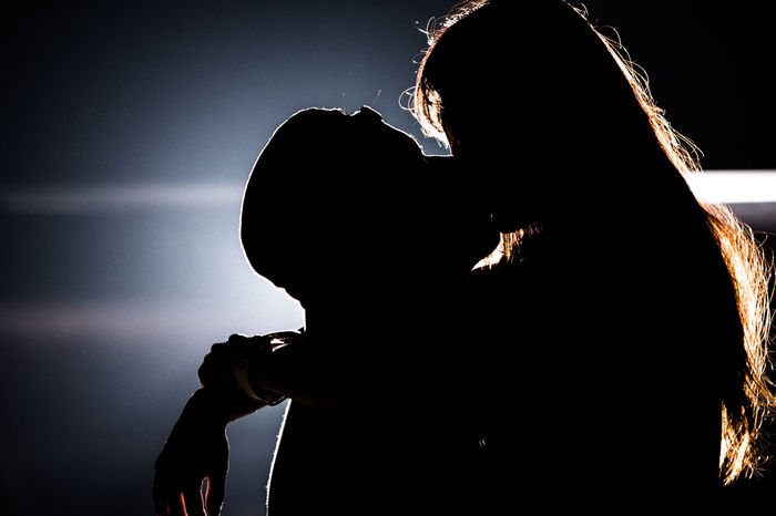 Silhouette man and woman kissing at night