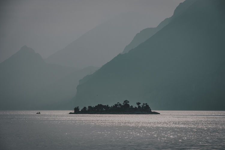 Silhouette mountain by sea against sky