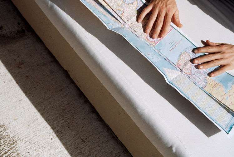 Cropped hands with map on bed