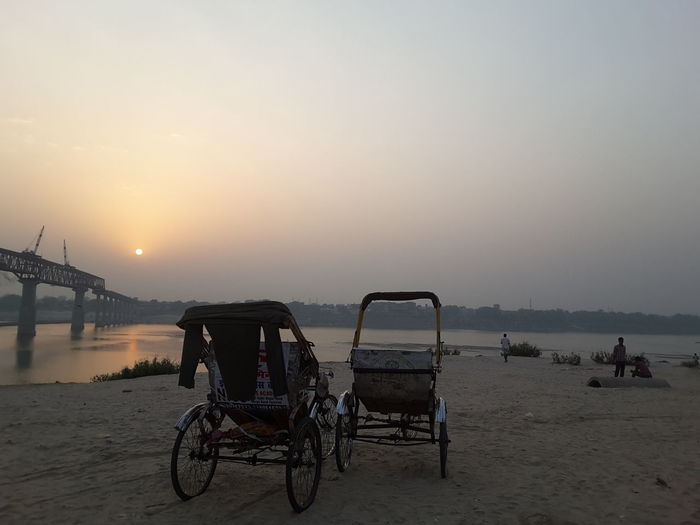 Bicycles on beach against clear sky during sunset