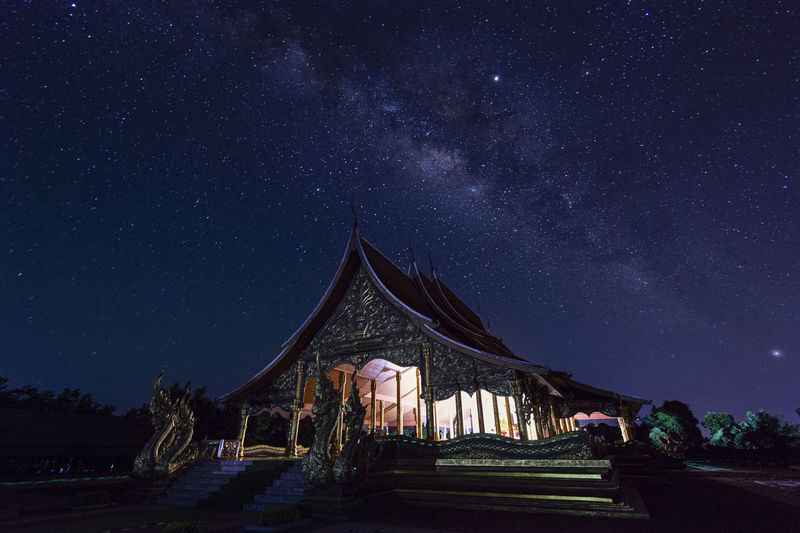 Low angle view of illuminated temple against star field at night